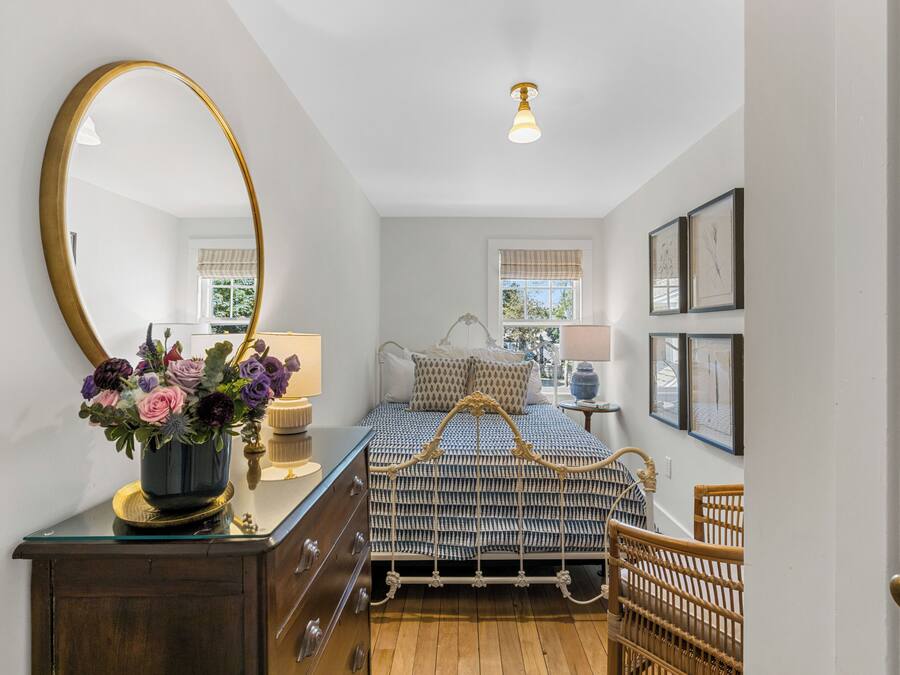 Ein Schlafzimmer mit Bett, Schminktisch, Spiegel und gerahmten Bildern an der Wand.