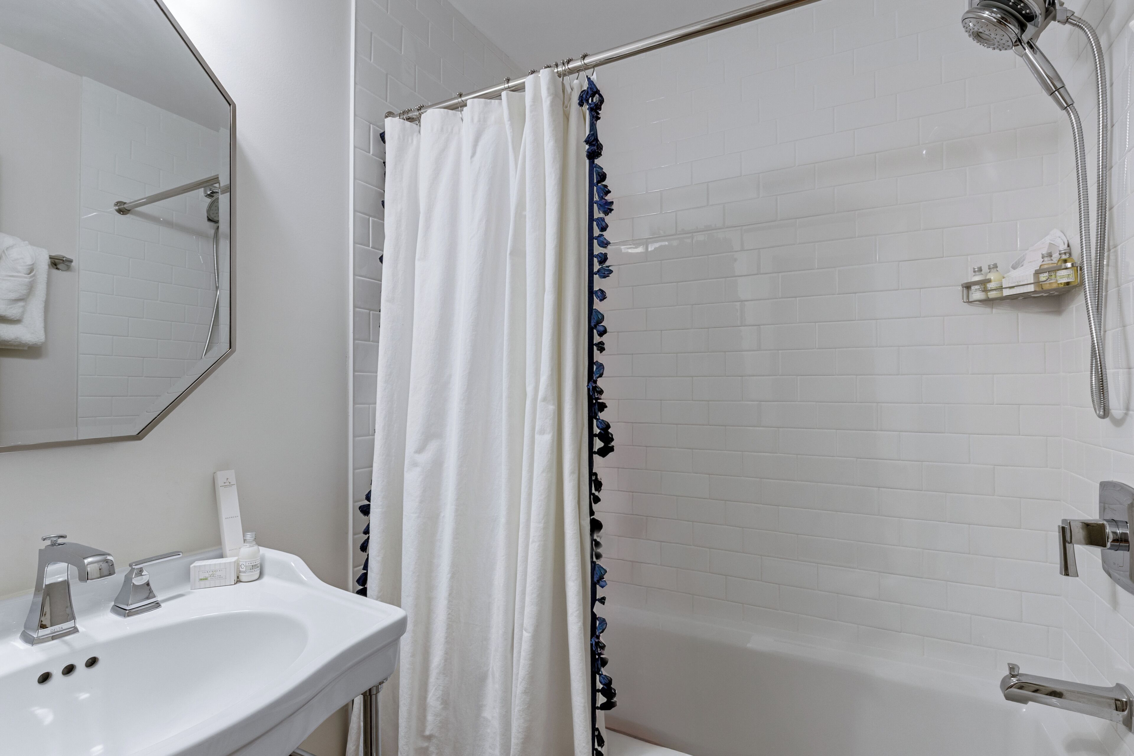 Une salle de bain avec un lavabo blanc, un miroir, une douche avec un rideau et une baignoire.