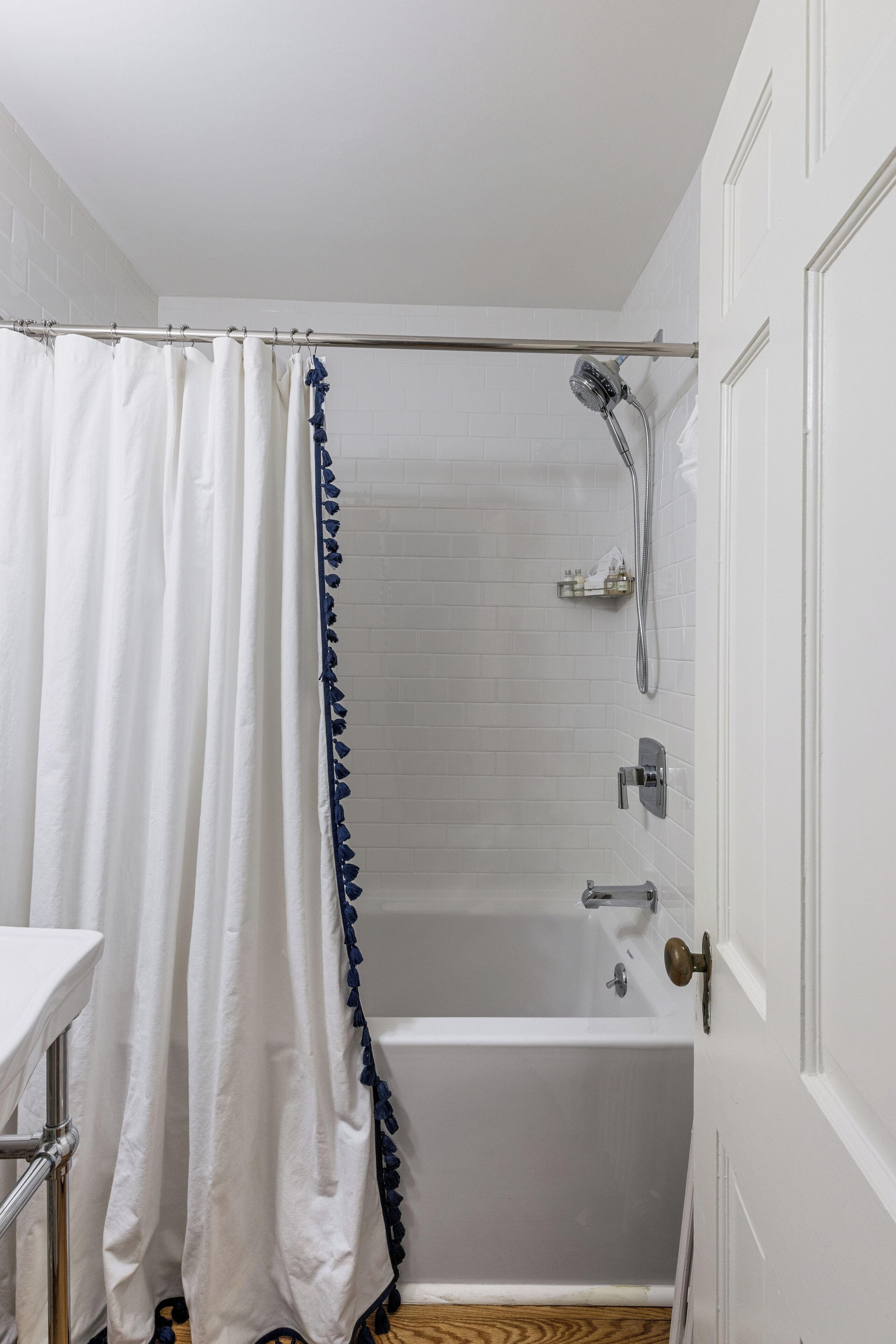 Un baño con bañera, ducha y una puerta blanca.
