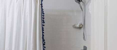 Un baño con bañera, ducha y una puerta blanca.
