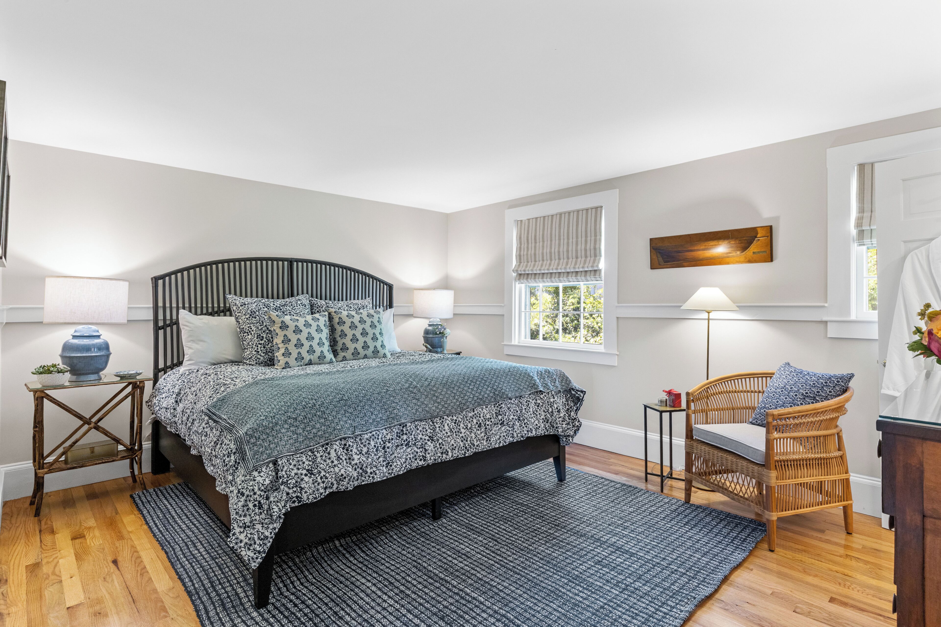 A bedroom with a bed, bedside tables, a chair, a window, and a painting on the wall.