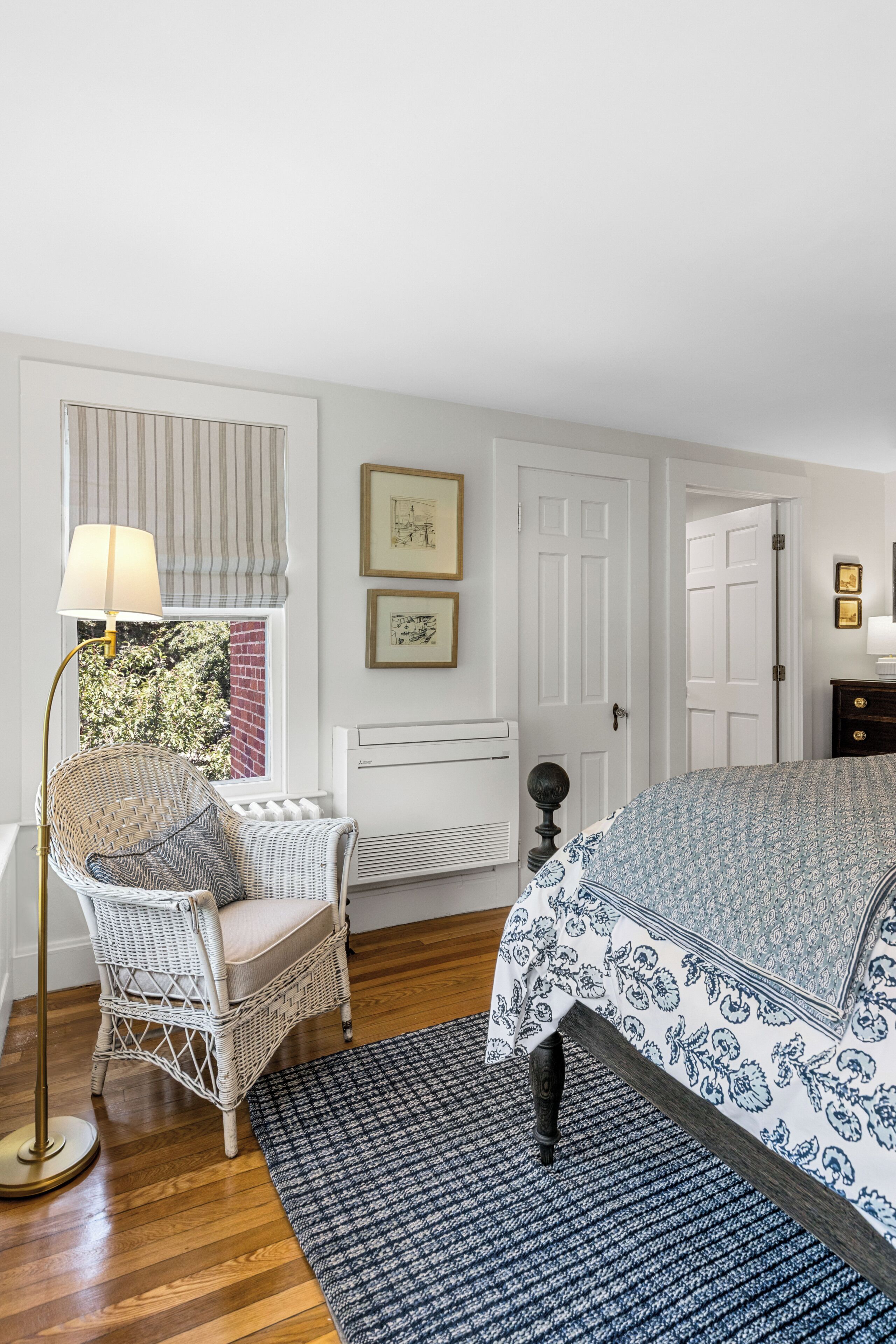 Une chambre à coucher avec un lit, une chaise, une lampe sur pied et un radiateur.