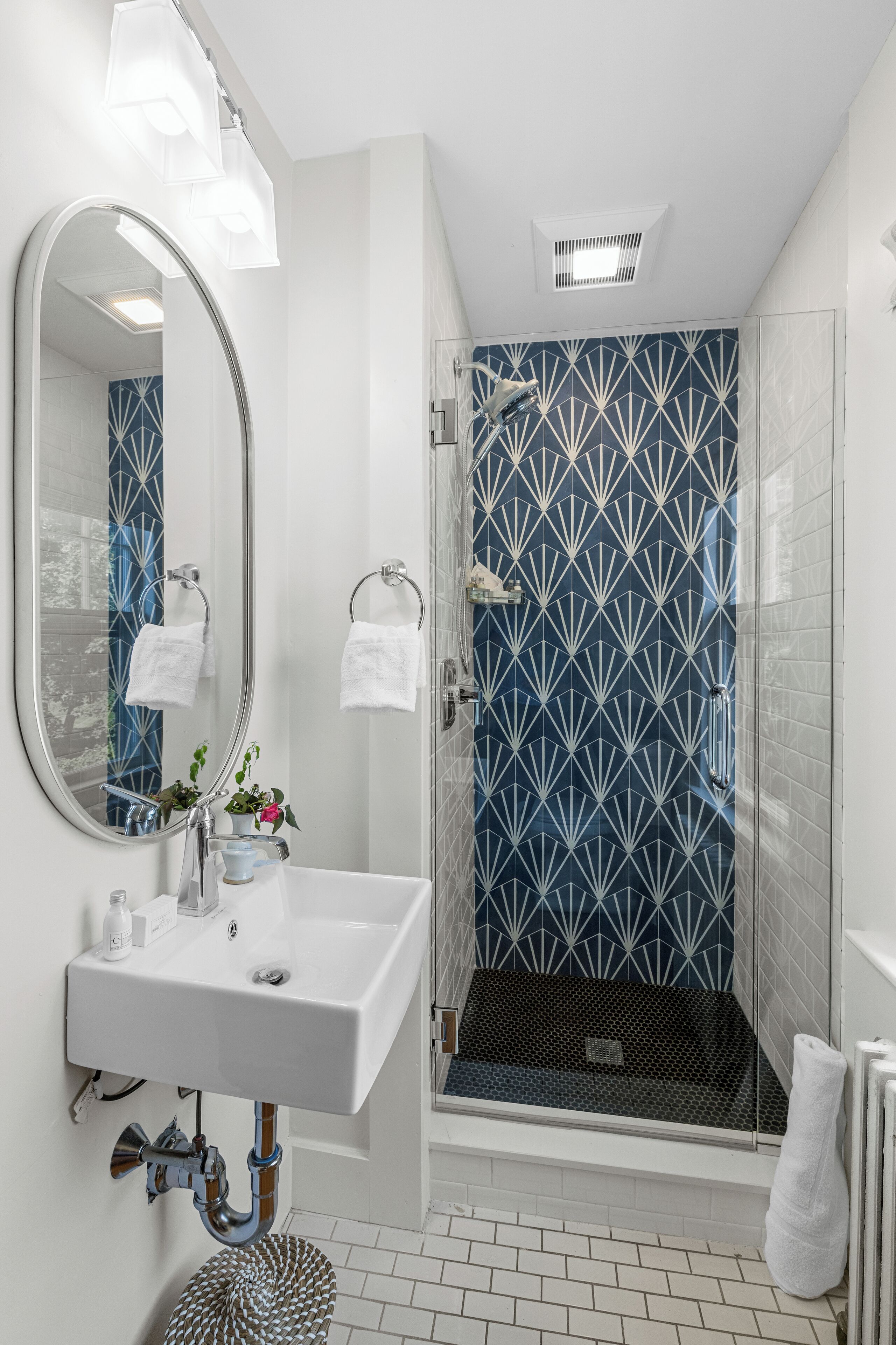 A modern bathroom with a white sink, mirror, and shower.