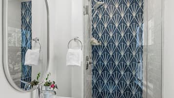 A modern bathroom with a white sink, mirror, and shower.