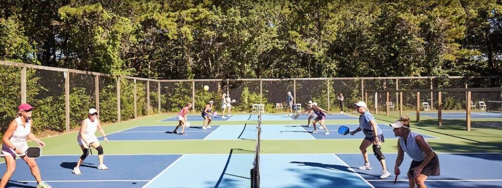 A tennis court with multiple players, surrounded by trees.
