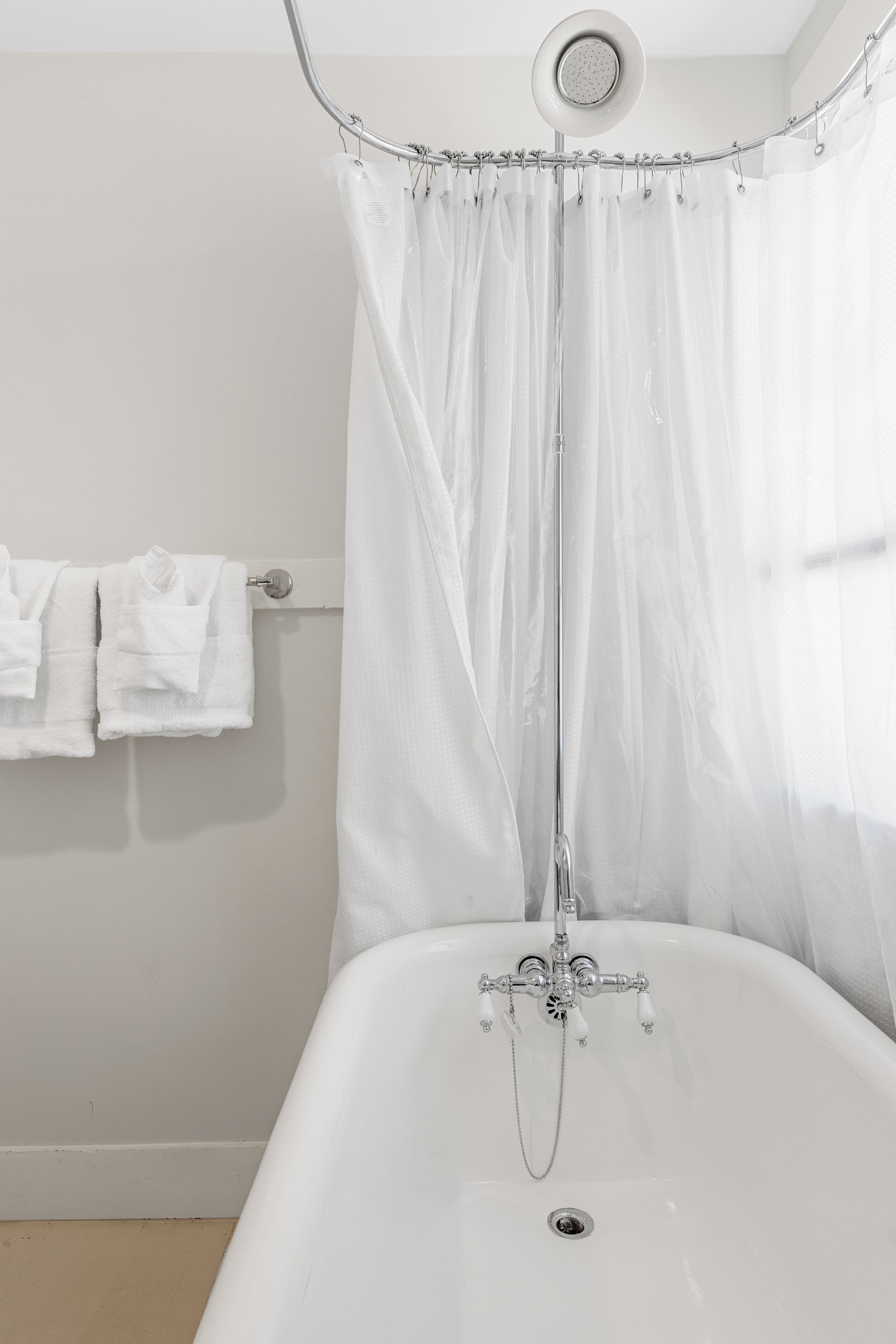A bathroom with a bathtub, a shower curtain, and two towels hanging on a rack.