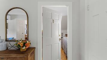Una habitación con un aparador de madera, un espejo y una puerta blanca que da a otra estancia.