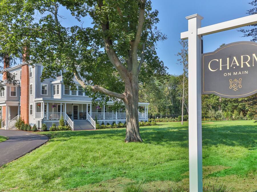 A large, two-story house with a porch and a sign that reads "Charm on Main."
