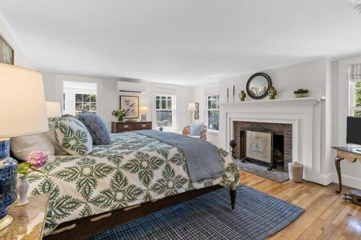 A bedroom with a bed, a fireplace, and a window.
