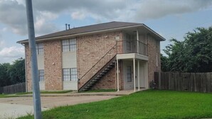 A two-story house with a brick exterior, a front porch, and a staircase leading to the second floor.