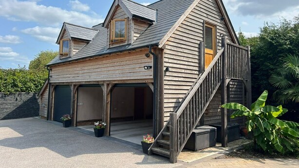 A two-story wooden house with a sloped roof, a front porch, and a staircase leading to the upper level. - Charming Countryside Barn Retreat – Perfect for Relaxing Escapes (East Preston)