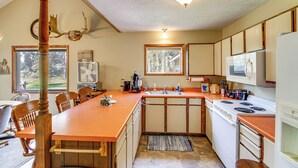 Una cocina con una mesa de madera, un fregadero, una estufa y armarios.
