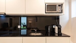 A modern kitchen with a built-in microwave, a coffee machine, and a kettle. - Central Porto Hideaway with Sunny Terrace by Lisbeyond (Porto)