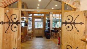 Un arco de madera da paso a una habitación con suelo de baldosas, un banco de madera y una mesa con sillas.