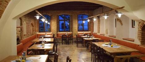 A restaurant with a rustic interior, featuring brick walls, wooden tables, and benches.