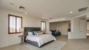 A spacious bedroom with a large bed, a sitting area with a sofa, and a separate room with a door leading to another space. - Amazing Litchfield Estate With Backyard Oasis! (Litchfield Park)