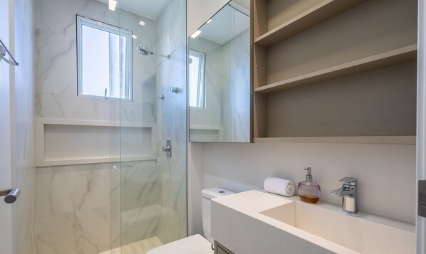 A modern bathroom with a glass shower enclosure, a white sink, and a large mirror.