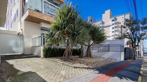 A residential area with modern buildings, a paved courtyard, and a palm tree. - Sophisticated Stay 200m From Praia Brava - EHI (Itajai)