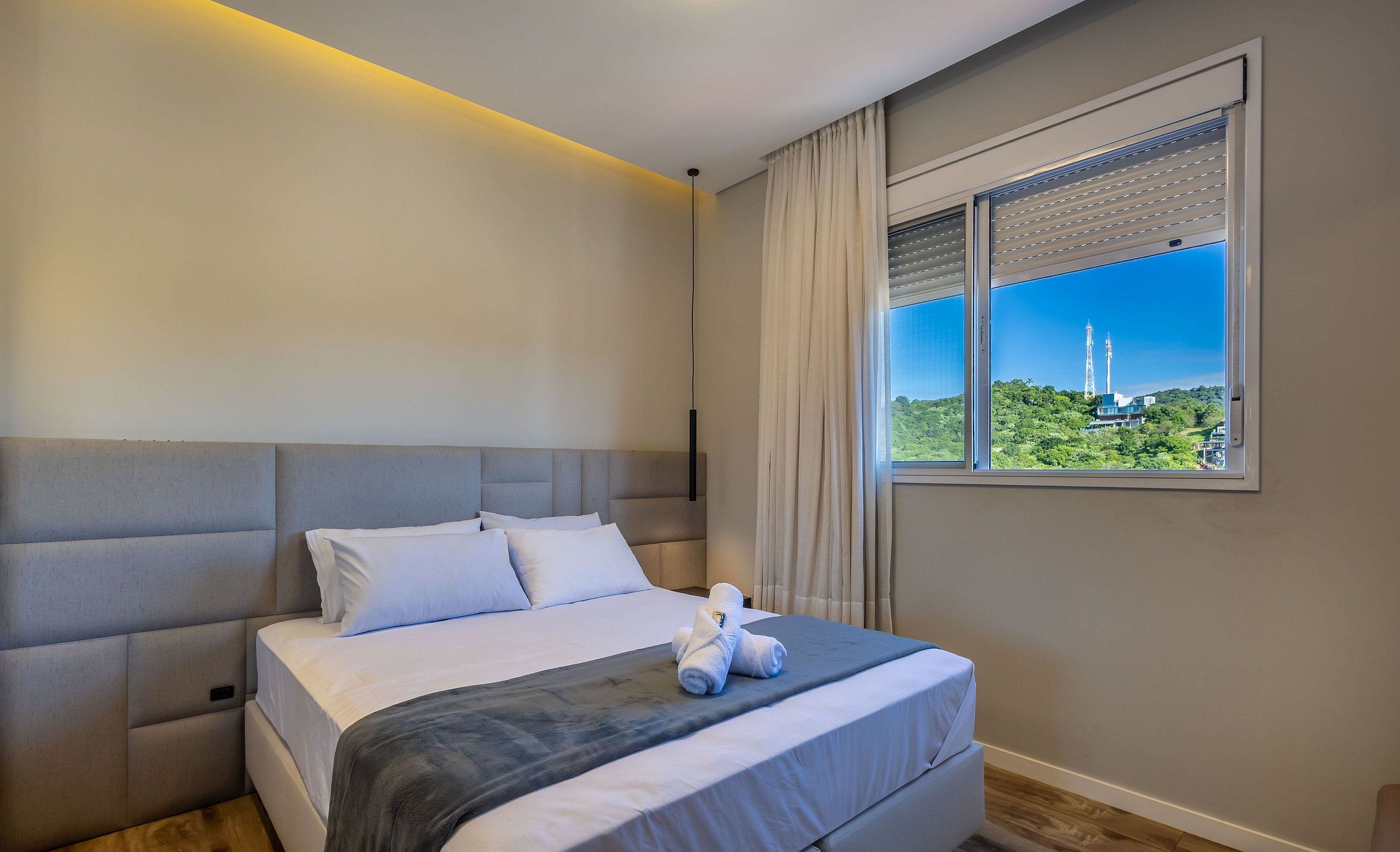 Una habitación de hotel moderna con una cama grande, vistas a una torre y una ventana con persianas.