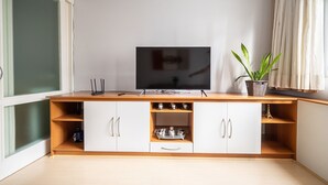 A modern living room with a flat-screen TV on a wooden console, a potted plant, and a glass door. - Well Equipped apt in BC Center 300m fr/ sea Ecp055 (Balneário Camboriú)