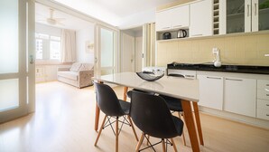A modern kitchen with white cabinets, a dining table with black chairs, and a ceiling fan. - Well Equipped apt in BC Center 300m fr/ sea Ecp055 (Balneário Camboriú)