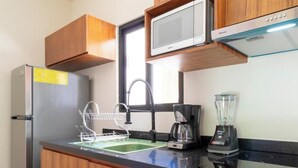 Una cocina moderna con armarios de madera, un refrigerador de acero inoxidable, un microondas, una cafetera y una licuadora.