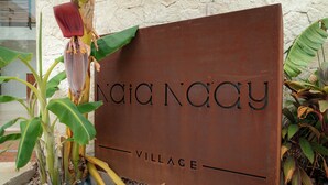 Un letrero con el texto 'Naia Naay Village' que indica un lugar o establecimiento.
