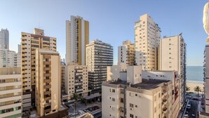 Een hoogstaand stedelijk gebied met meerdere appartementencomplexen, een zichtbare straat en een strand op de achtergrond.