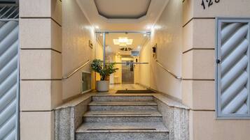 A hotel entrance with a staircase leading to the lobby, a potted plant, and a sign indicating the entrance.