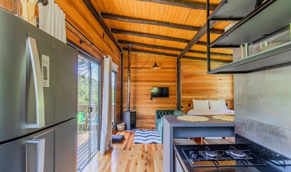 A compact cabin with a kitchenette, a bed, and a TV.
