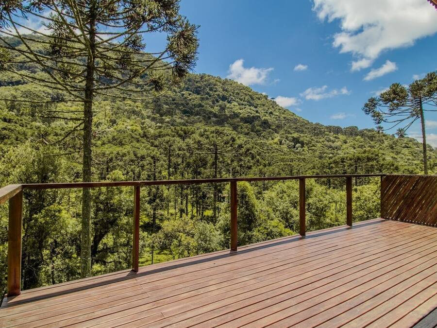 Una terraza de madera con barandilla metálica que da a una ladera boscosa.