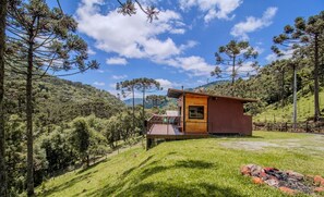 A cabin with a wooden deck, surrounded by a forested hillside. - Comfortable Cabin With Heater Urubici-sc Egc001 (Urubici)