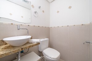 Une salle de bain avec un lavabo, des toilettes et une douche, le tout de couleur blanche.