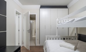 Ein Schlafzimmer mit Etagenbett, Nachttisch und Kleiderschrank.