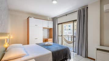 A bedroom with a bed, a wardrobe, a desk, and a balcony with a hammock.