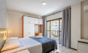 Un dormitorio con cama, armario, escritorio y balcón con hamaca.