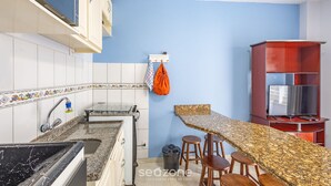 A kitchen with a granite countertop, a sink, and a wooden bar area with stools. - Beachfront Apartment in BC Great Location Eit302 (Balneário Camboriú)
