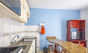 A kitchen with a granite countertop, a sink, and a wooden bar area with stools.