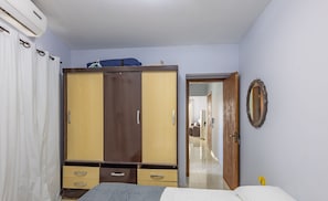Une chambre à coucher comprenant un lit, une armoire, un miroir et une porte donnant sur une autre pièce.