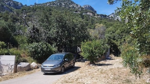 Un automóvil estacionado en un camino de grava, con montañas al fondo.