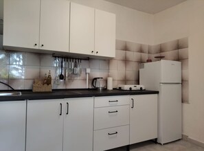 A kitchen with white cabinets, a black countertop, and a white refrigerator.