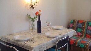 A dining table with a newspaper tablecloth, two plates, a wine bottle, and a vase with flowers. - Apartments A&N Pakoštane - One Bedroom Apartment with Sea View and Balcony (A1) (Pakoštane)