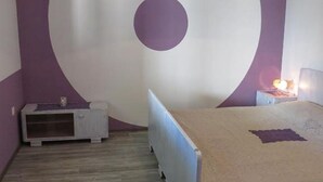 A bedroom with a bed, a nightstand, a dresser, and a wall with a large circular design. - Apartments A&N Pakoštane - Two Bedroom Apartment with Terrace (A3) (Pakoštane)