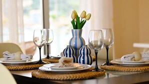 Una mesa de comedor con platos, vasos y un jarrón con tulipanes.