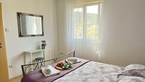Un dormitorio con cama, escritorio y ventana con cortinas.