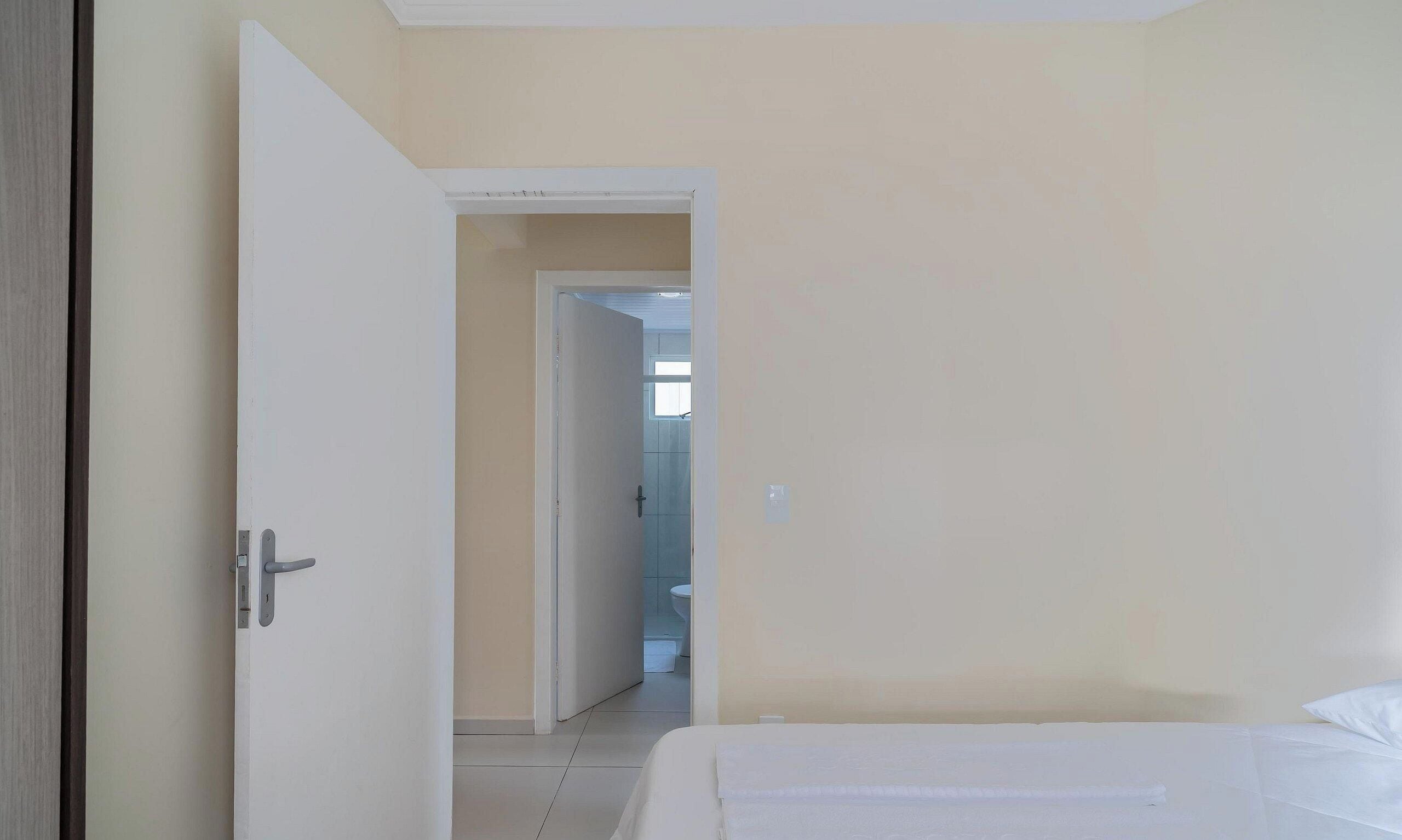 Ein Hotelzimmer mit einem Bett, einer Tür zu einem Badezimmer und Blick auf den Flur.