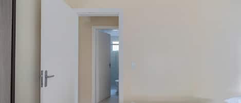 A hotel room with a bed, a door leading to a bathroom, and a view of the hallway.