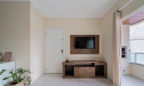 Sala de estar moderna com televisão de tela plana na parede, mesa de console de madeira e uma porta.