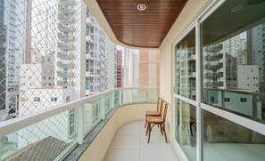 Un balcon doté d’un plafond en bois, de rampes en verre et offrant une vue sur les immeubles de grande hauteur.