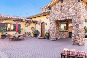 Un patio con pared de piedra, puerta de madera y una mesa con sillas.